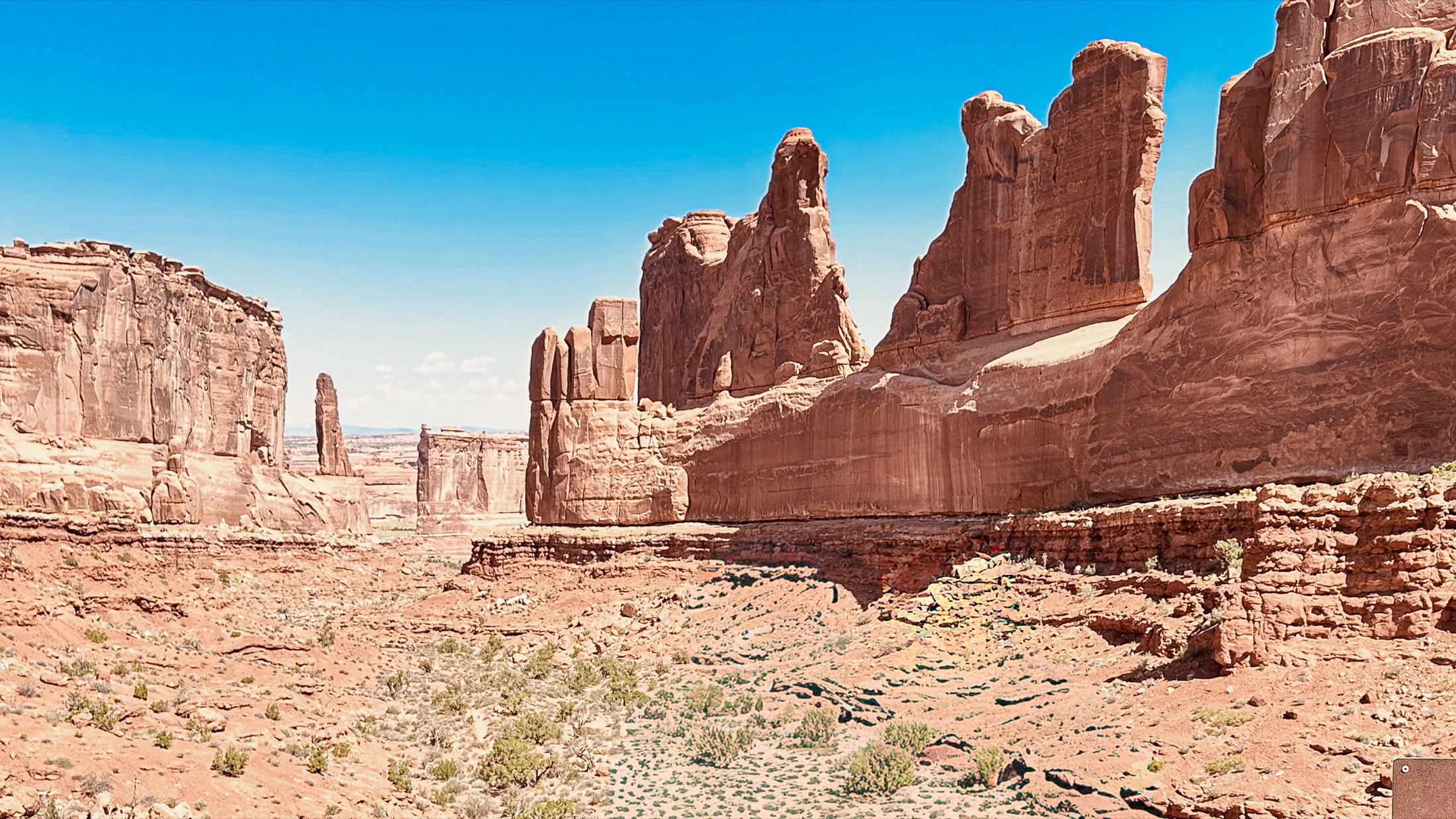 Tall red sandstone walls and towers beneath a bright blue sky in Arches National Park