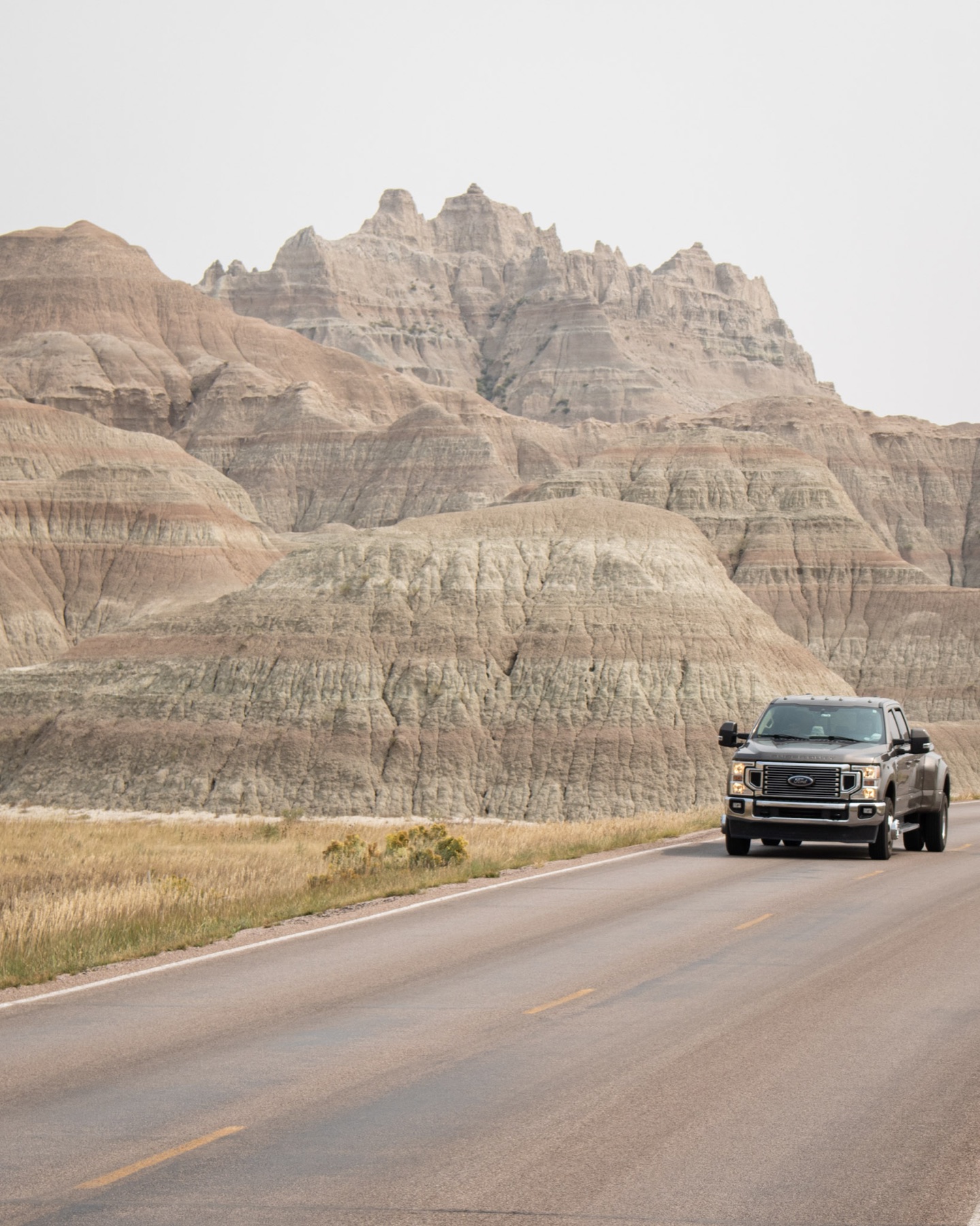 A pickup truck driving beneath Badlands rock pinnacles