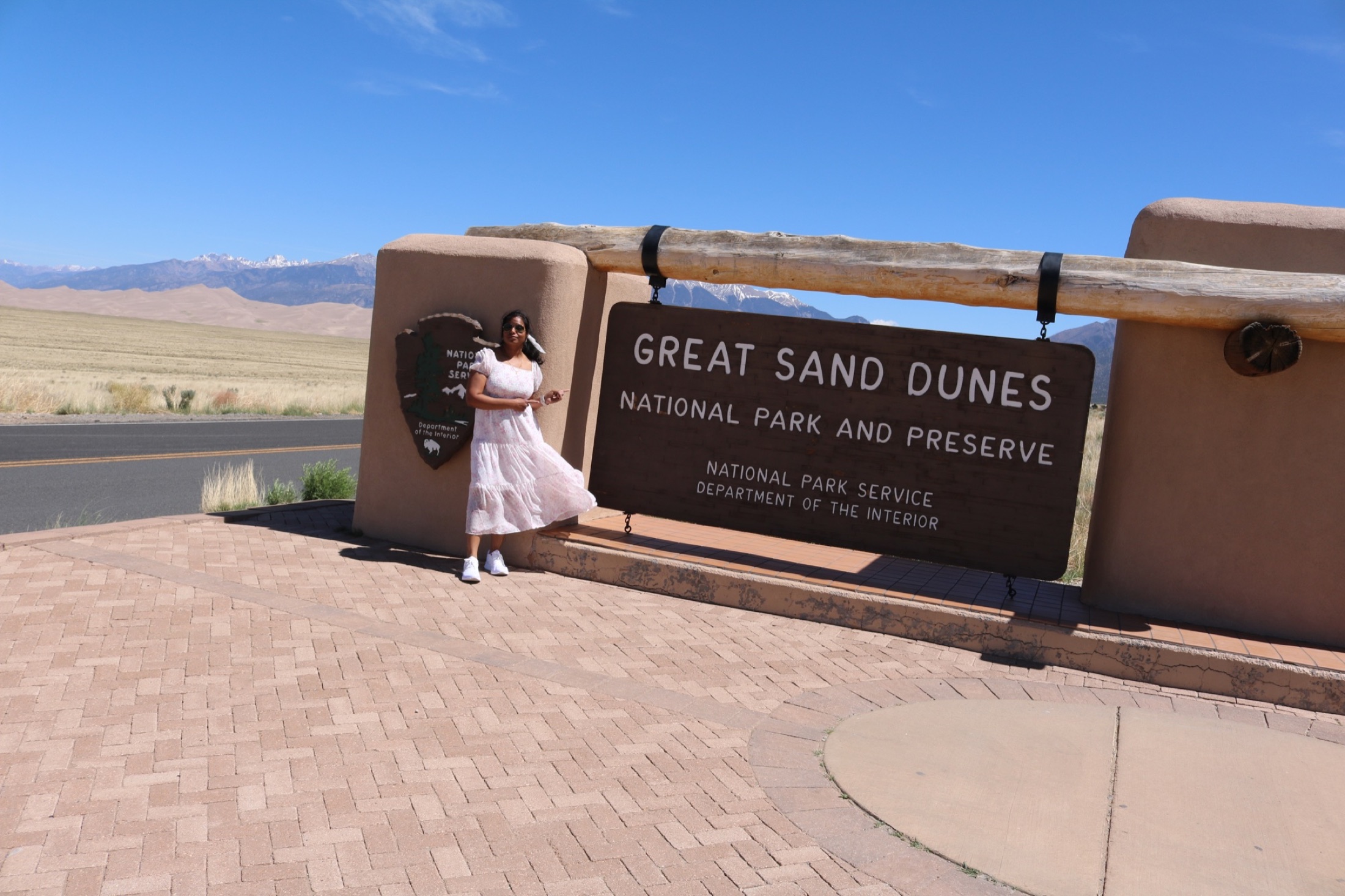 Traveler beside the Great Sand Dunes National Park and Preserve entrance sign