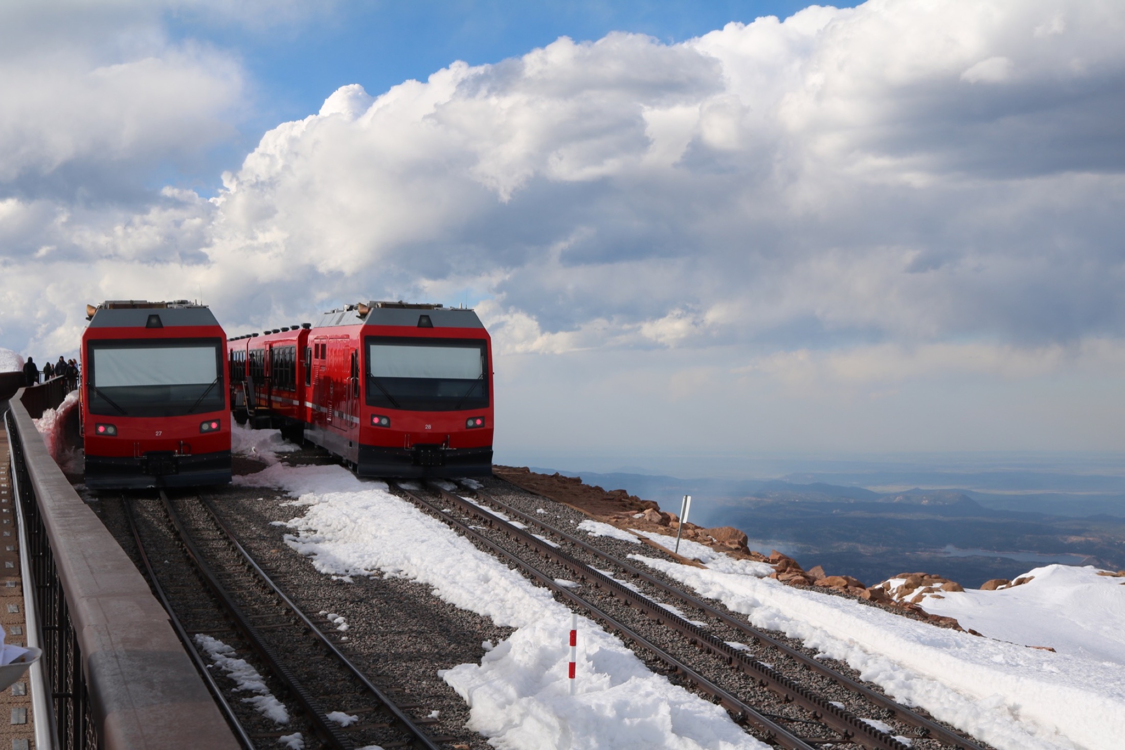 Red cog railway trains at the snowy summit of Pikes Peak
